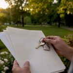 Homeowner holding mortgage papers and keys outside home
