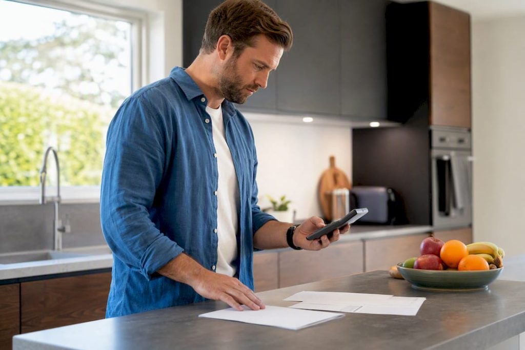 Hands using calculator and loan documents at kitchen table