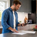 Hands using calculator and loan documents at kitchen table